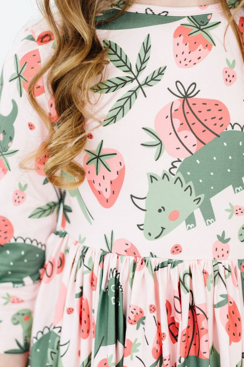 Close-up of the 'Hear Me Roar' 3/4 Sleeve Pocket Twirl Dress for Girls, highlighting the adorable dinosaur and strawberry patterns on the fabric.