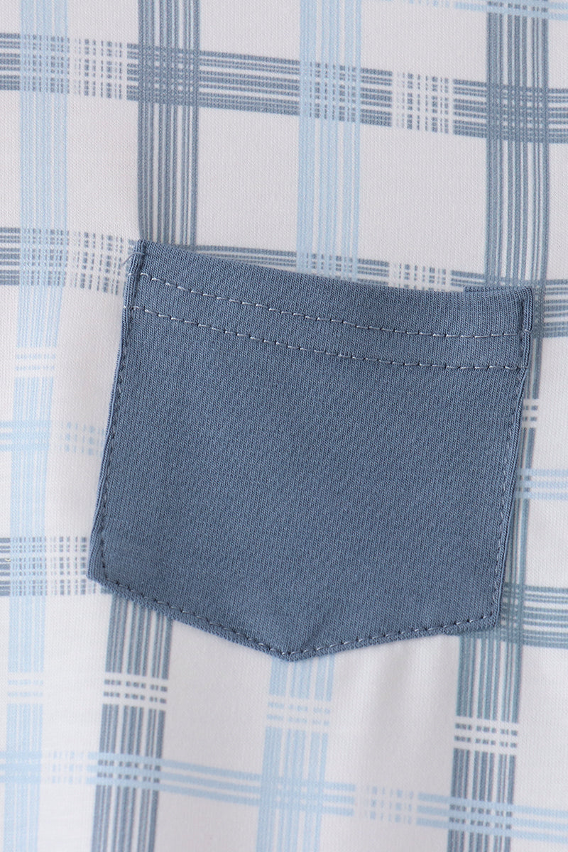 Close-up of pentagon-shaped blue chest pocket with double stitching on blue and white plaid fabric