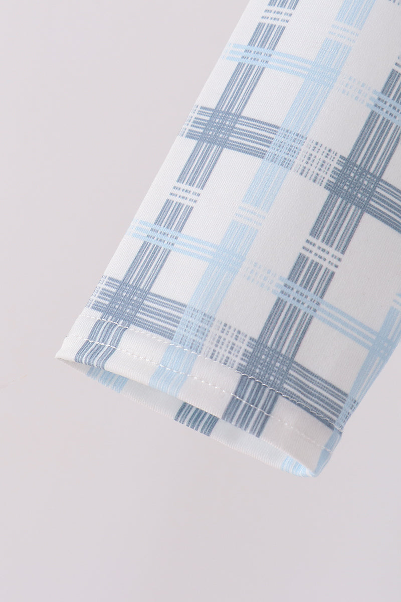 Macro shot of sleeve cuff hem showing intersecting dark and light blue grid lines on white plaid print