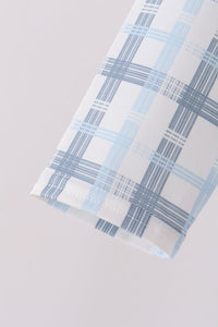 Macro shot of sleeve cuff hem showing intersecting dark and light blue grid lines on white plaid print