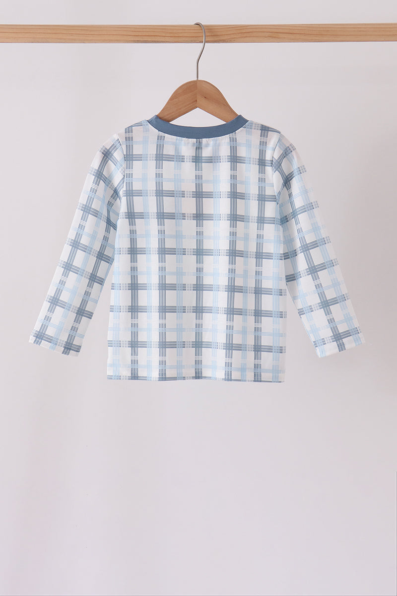 Rear view of blue plaid long sleeve top hanging on hanger with solid blue neckline trim