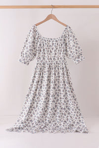 White dress with small teal and pink floral print, featuring puff sleeves, smocked bodice, and square neckline for modern mom style.