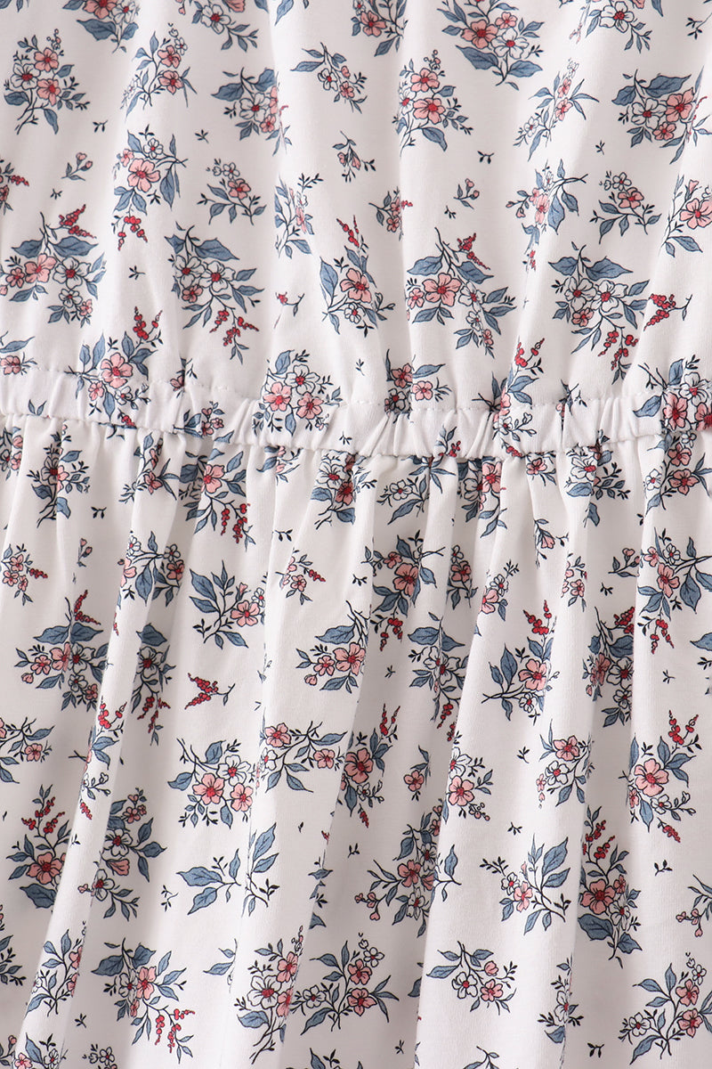 White dress fabric with blue and pink botanical print, featuring an elastic gathered waist seam for a comfortable, flattering fit.