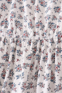 White dress fabric with blue and pink botanical print, featuring an elastic gathered waist seam for a comfortable, flattering fit.