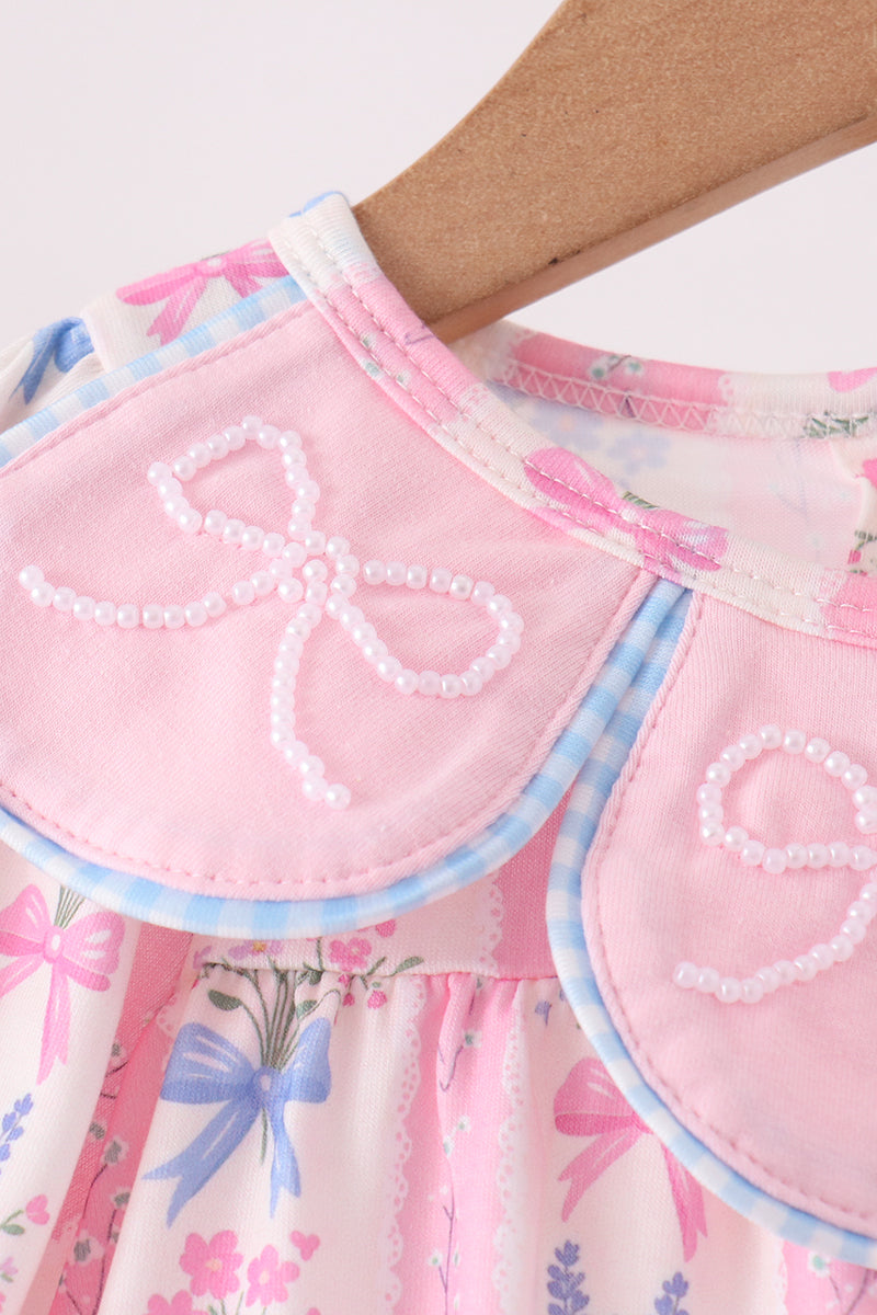 Close-up of pink scalloped collar with blue gingham trim and pearl bead bows