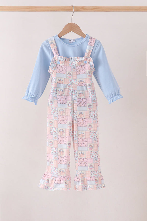 Pink pumpkin patchwork ruffle dungarees paired with a light blue long-sleeve top. Adorable fall outfit for girls.