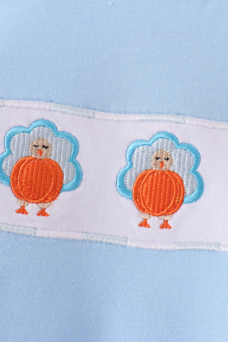 Blue baby romper featuring two charming orange and blue embroidered turkeys on a white fabric strip.