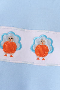 Blue baby romper featuring two charming orange and blue embroidered turkeys on a white fabric strip.