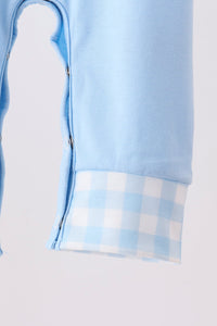 Light blue baby romper sleeve detail with side snap buttons and a soft blue and white gingham cuff.