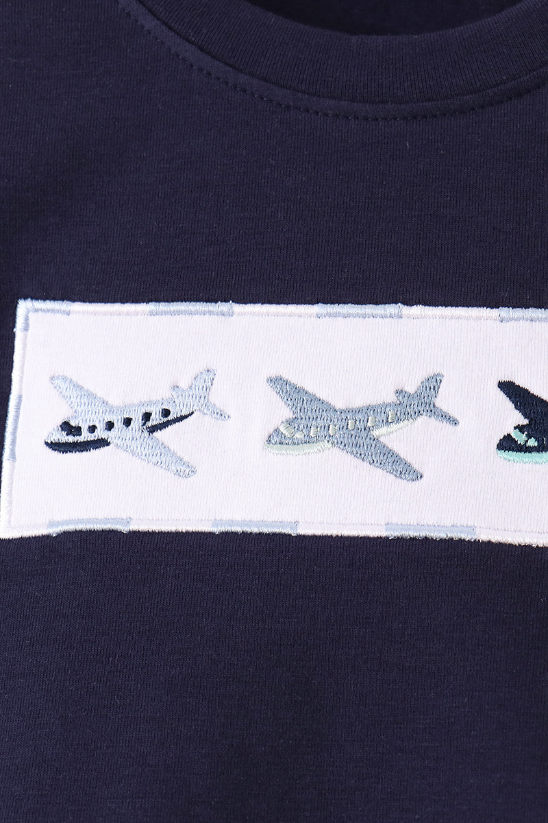 Close-up of embroidered light blue, grey, and navy airplanes on white chest patch
