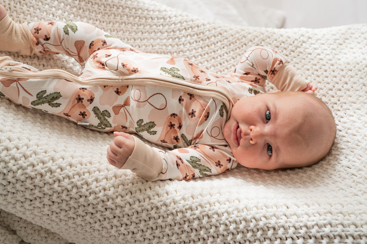 Angled view of convertible foot design and stretchy fit of cowgirl print bamboo romper