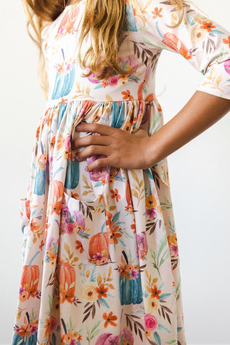 Detail shot of the Harvest Blooms 3/4 Sleeve Pocket Twirl Dress, showcasing the stylish pockets and whimsical floral patterns, great for young adventurers.