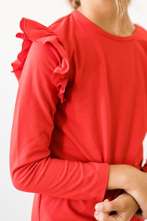 Close-up of a girl wearing a Red Long Sleeve Ruffle Tee, showcasing the charming ruffle detail on the sleeve, perfect for a stylish look.