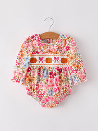 Fall floral baby romper with pumpkin embroidery, bow smock, and scalloped trim on a hanger.