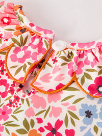 Close-up of pink floral smock dress collar with orange piping and a white button.