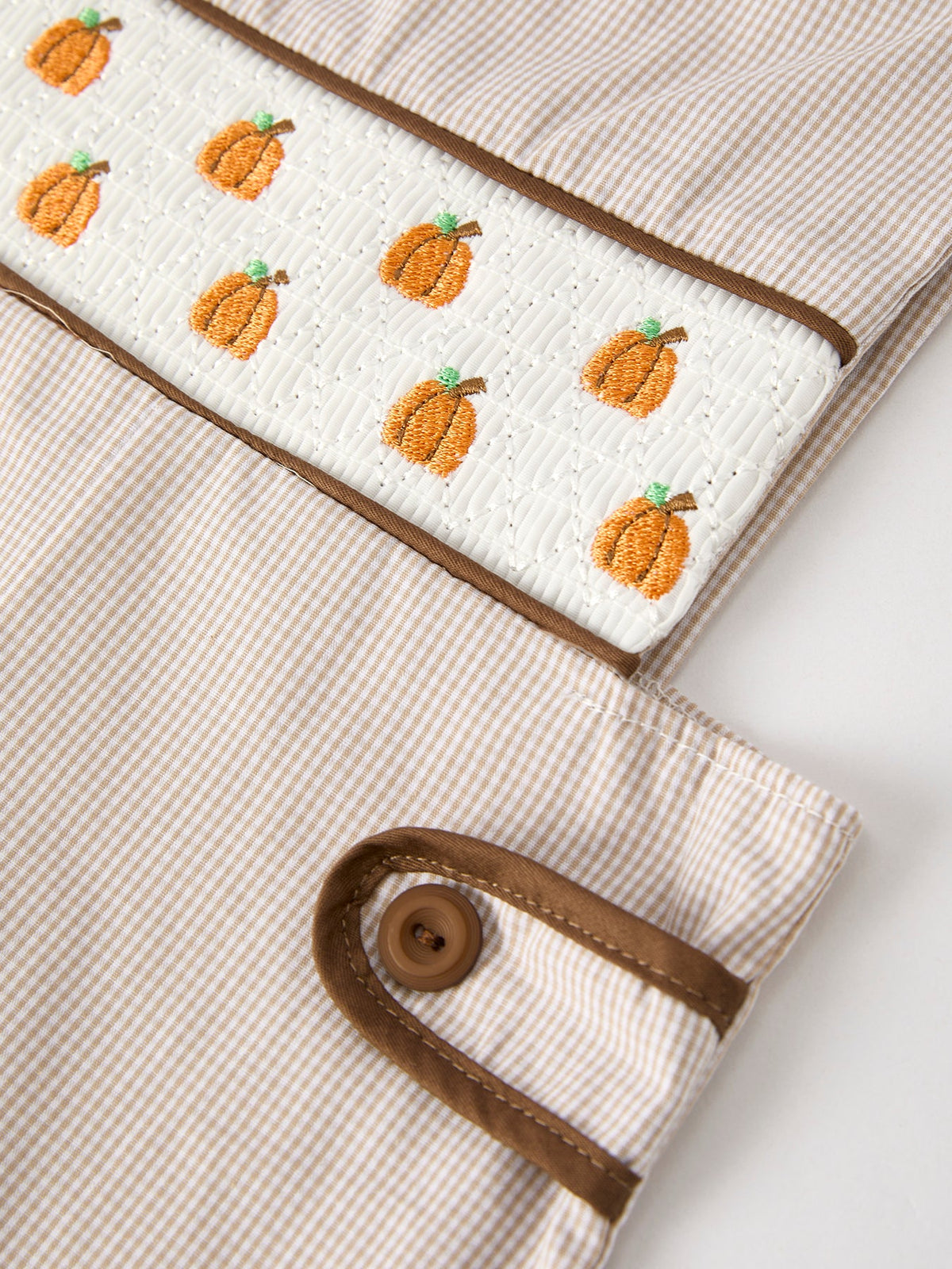 Fall pumpkin smock embroidery on white quilted panel of beige striped boys romper with brown trim