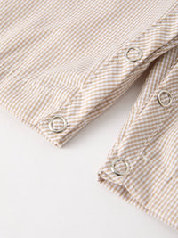 Close-up of beige striped romper fabric with silver snap buttons, part of fall pumpkin smock boys romper.