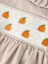 Beige striped smock border with white quilt panel featuring orange pumpkin embroidery for a fall girls' dress.