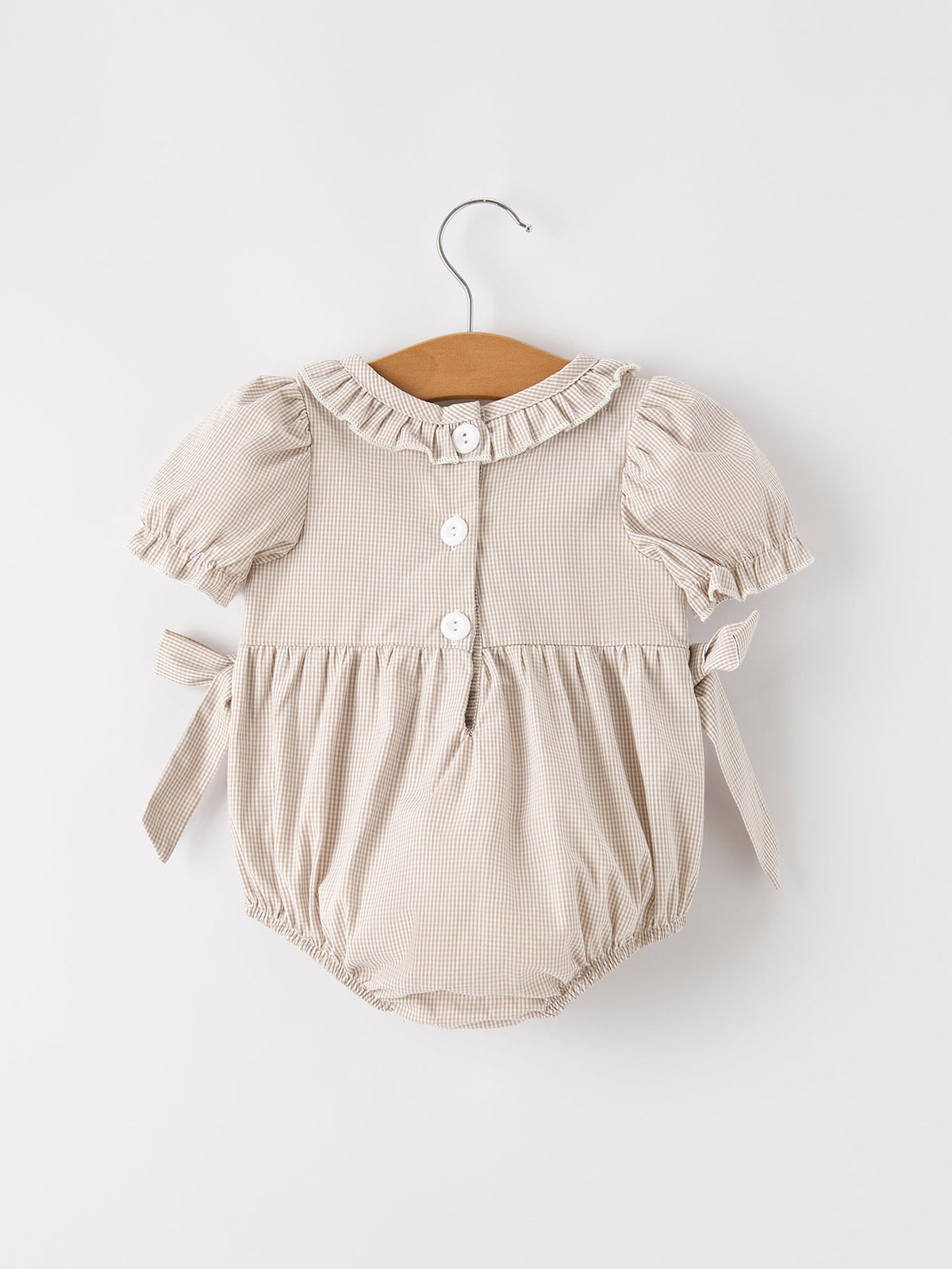 Beige plaid baby girl romper with puff sleeves, ruffled collar, front buttons, and tied sides.