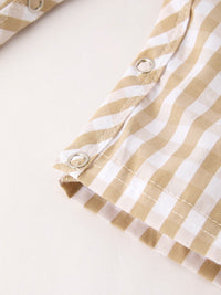 Apricot and white plaid baby romper fabric detail with silver snap buttons and neat stitching.