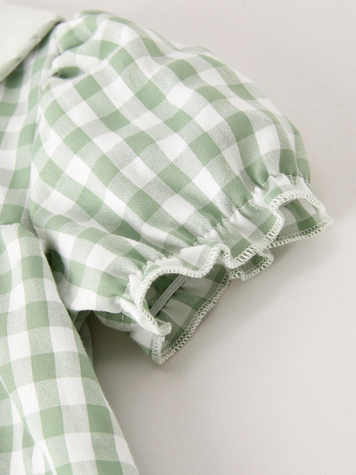 Close-up of green and white gingham plaid fabric with a scalloped ruffle edge.
