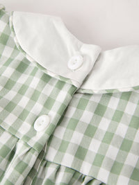 Close-up of a green plaid dress with a white collar and white buttons.