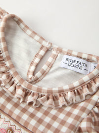 Close-up of Christmas vintage-style plaid dress with ruffled edge and Rylee Faith Designs label.