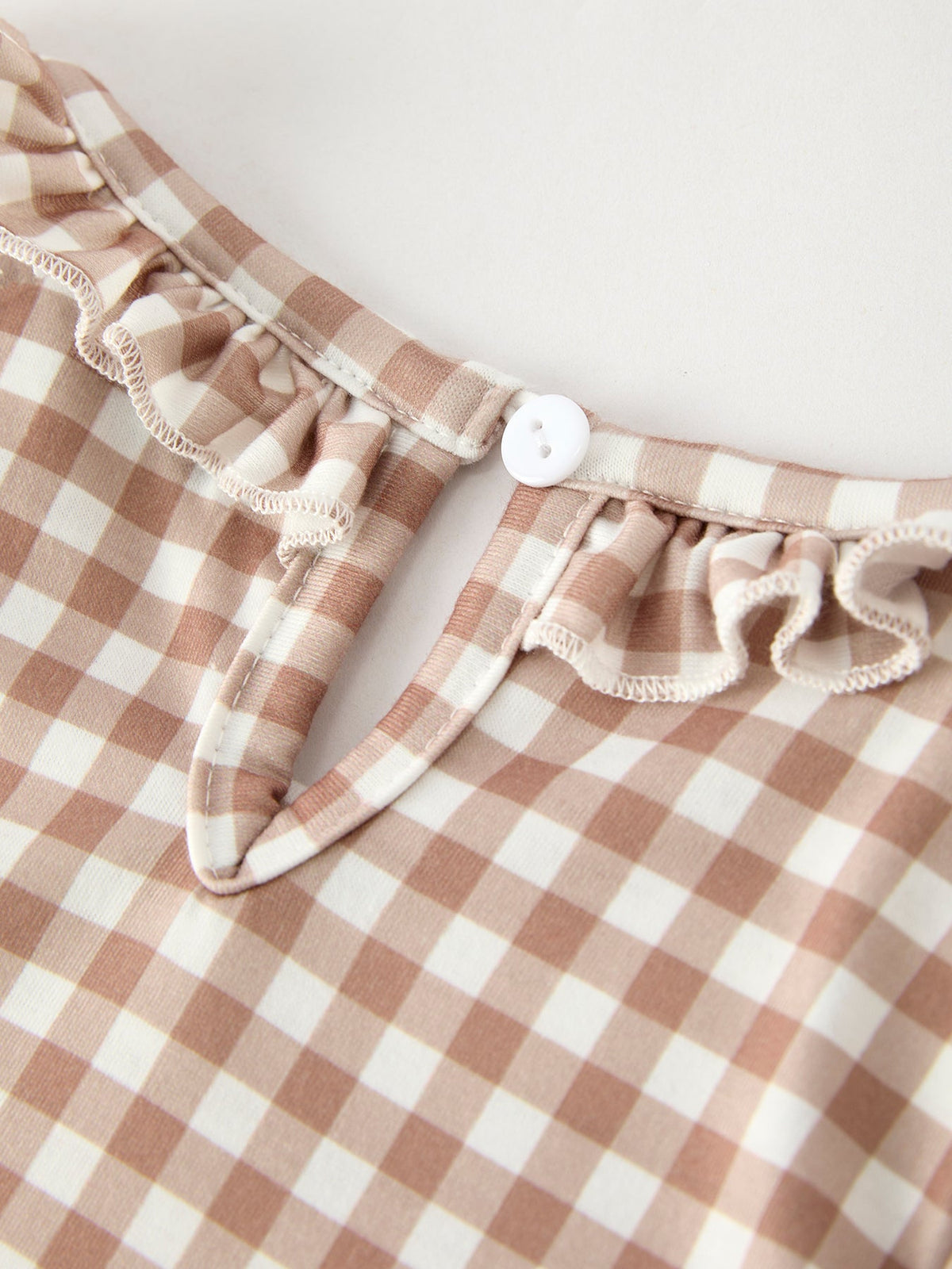 Beige and cream gingham dress fabric with a white button and delicate ruffle trim.