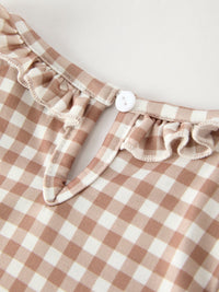Beige and cream gingham dress fabric with a white button and delicate ruffle trim.