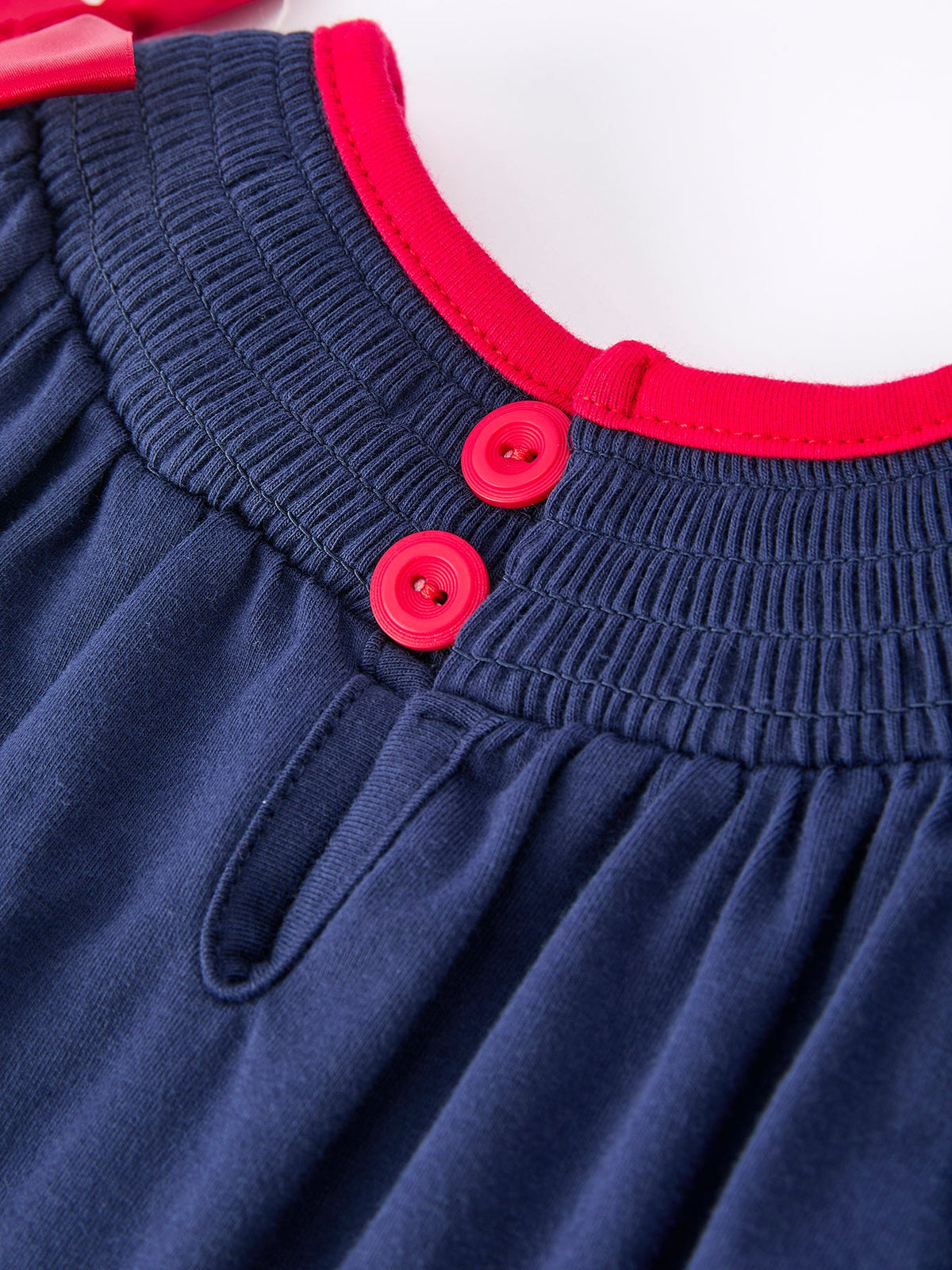 Navy baby romper waist with red trim, red buttons, and smocked elastic detail for a festive holiday outfit.