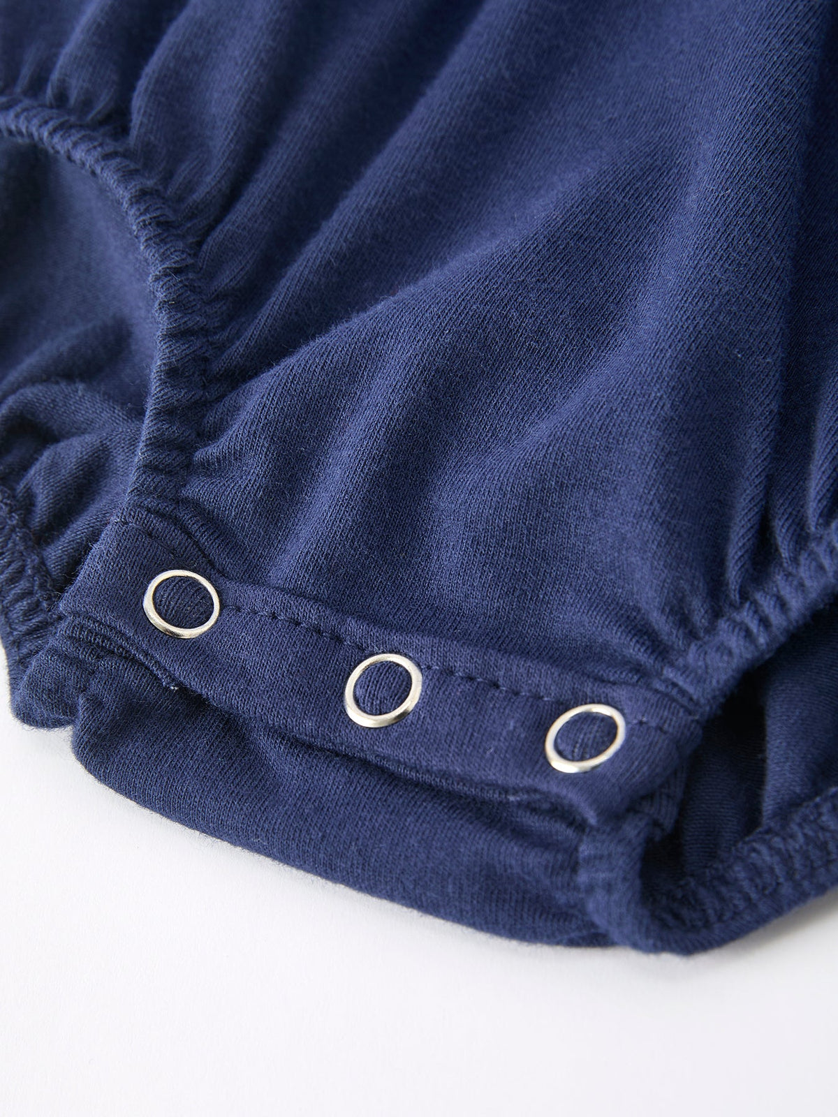 Navy baby romper leg detail featuring silver snap buttons and soft elastic fabric for easy diaper access.