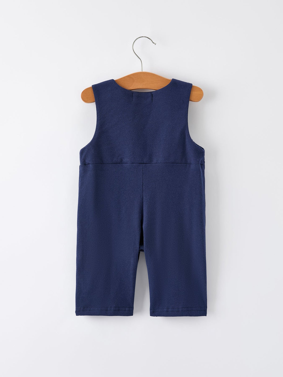 Back view of navy baby boys holiday romper on wooden hanger featuring Santa sleigh design for festive celebrations.