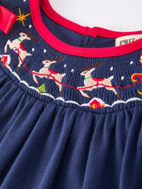 Navy blue Christmas dress with embroidered Santa sleigh, reindeer, and red trim. Festive holiday party attire featuring playful winter motifs.