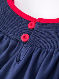 Navy Christmas dress bodice with red trim, bright red buttons, and smocked elastic waist detail.