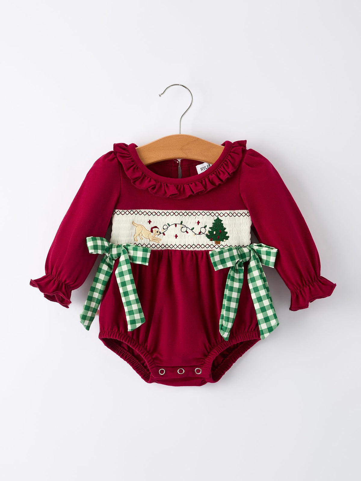 Red baby girl romper with festive Christmas embroidery of a dog and tree, featuring ruffled neckline and green plaid side ties.