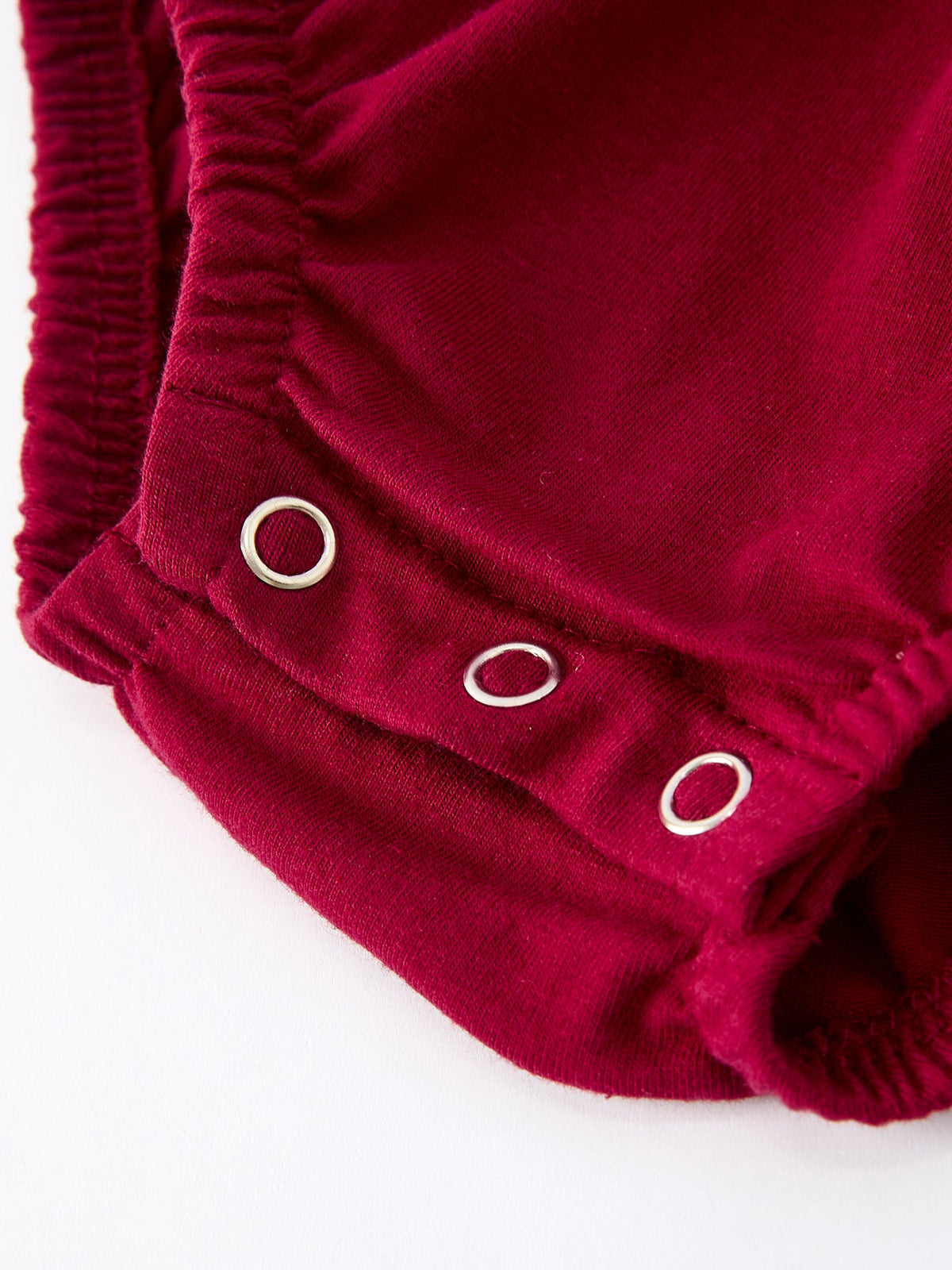 Red baby romper leg detail featuring silver snap buttons and elasticized hem for easy diaper changes.
