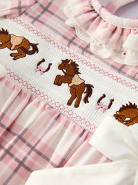 Brown horse and horseshoe embroidery on smocked white bodice with pink plaid ruffled baby girl romper.