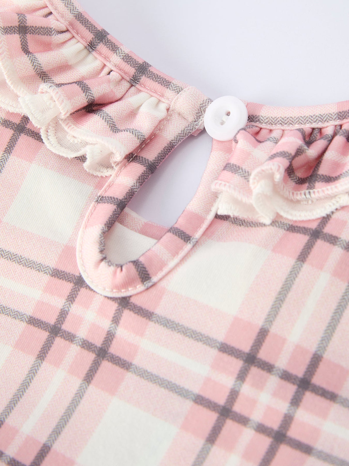 Pink plaid girls dress featuring a ruffled neckline with white button closure and classic western-inspired checkered pattern.
