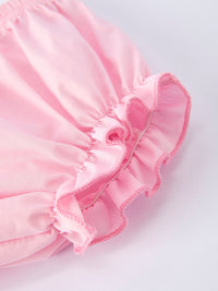 Close-up of pink fabric with ruffled trim from a floral smocked bishop bloomer set.