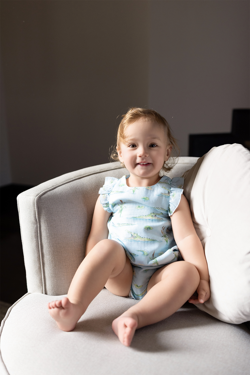 Gator Games Organic Muslin Bubble Romper on a smiling toddler in swamp print with alligators and lily pads.