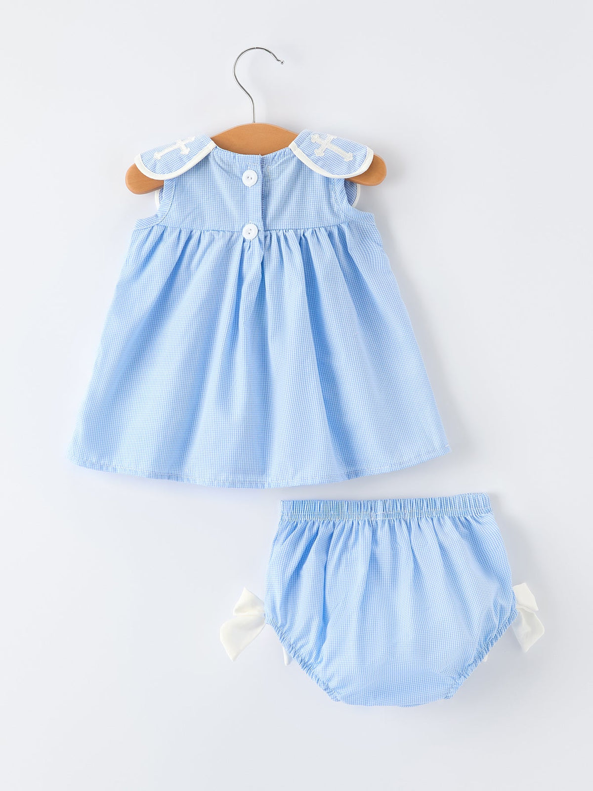 Blue gingham baby bloomer set with Peter Pan collar, embroidered crosses, and bow-tied shorts.