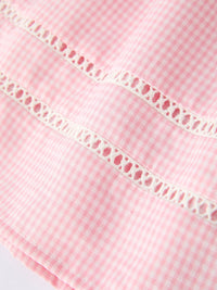 Close-up of pink gingham cotton fabric with white lace trim.