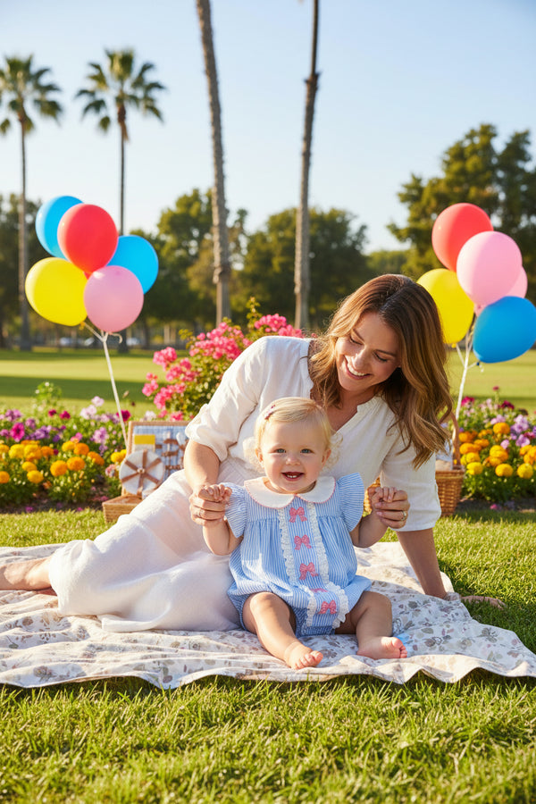 a six month old blonde girl with her mom at a park with balloons, palm trees and flowers