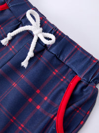 Navy plaid shorts with a white rope drawstring and red piping, close-up.