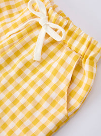 Close-up of yellow and white gingham fabric with a white bow tie detail.
