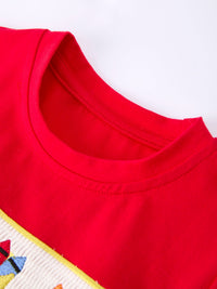 Close-up of red cotton top from back-to-school smocked set, featuring a yellow-trimmed plaid bib and round neckline.