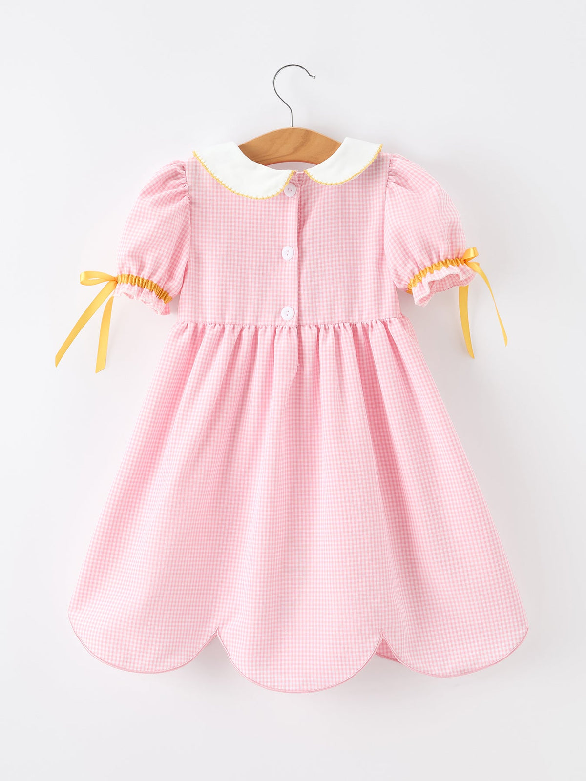 Back view of the Girls Back To School Pencil Twirl Dress with bow appliques, showcasing the stylish design and button details.
