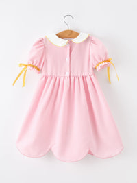 Back view of the Girls Back To School Pencil Twirl Dress with bow appliques, showcasing the stylish design and button details.