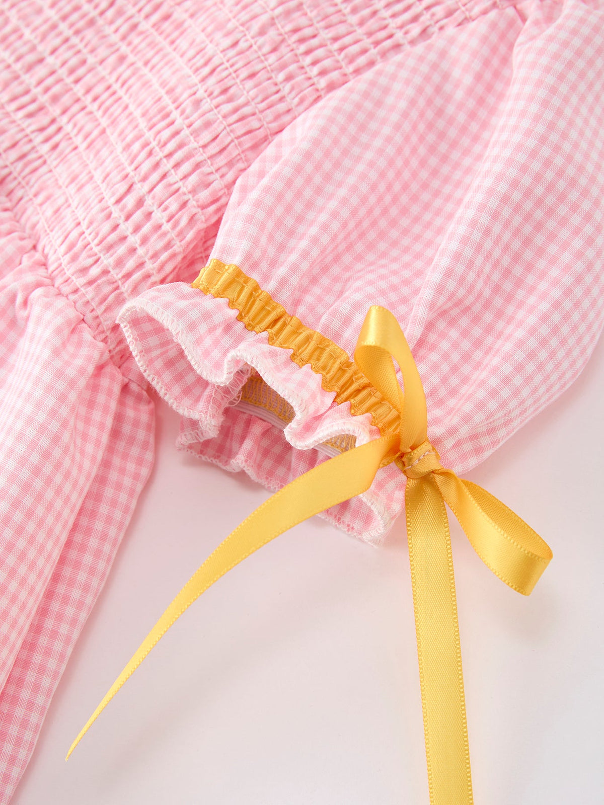 Close-up of the sleeve detail on the Girls Back To School Pencil Twirl Dress featuring a smocked design and a yellow ribbon tie by Rylee Faith Designs.