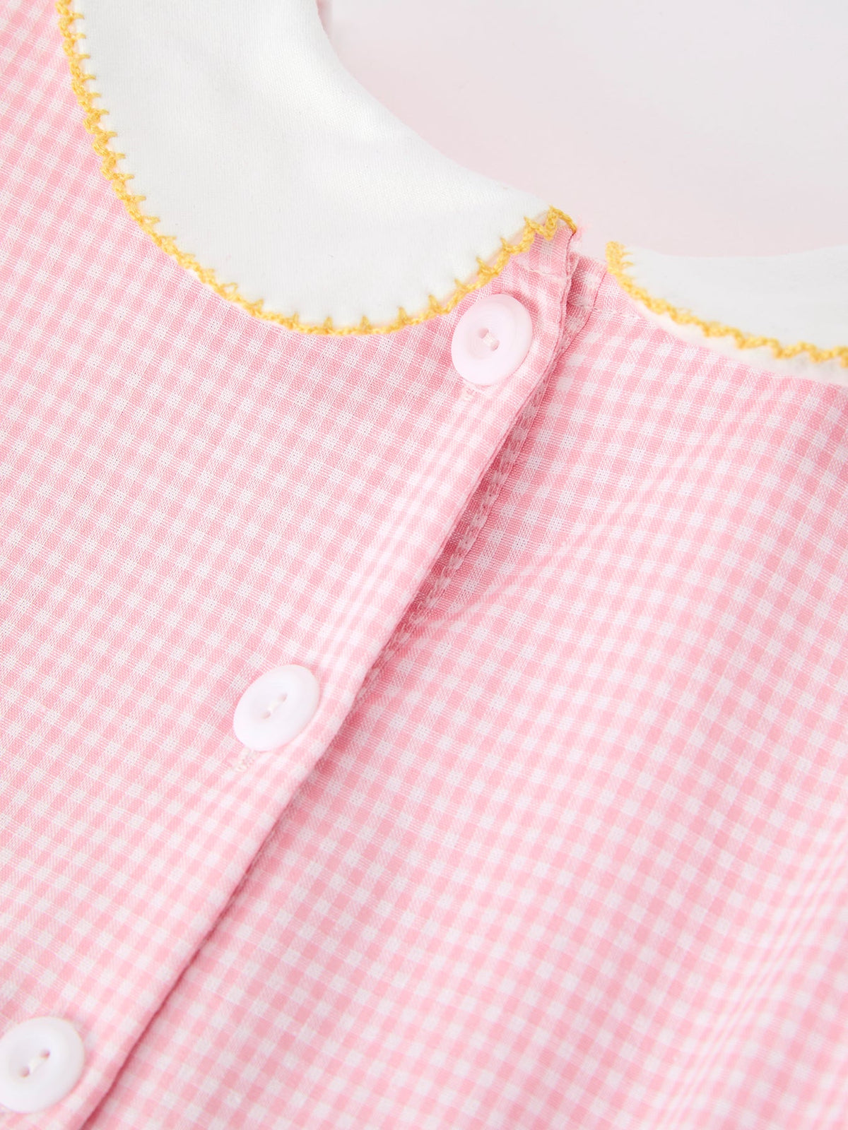 Detail shot of the collar and button closure on the Girls Back To School Pencil Twirl Dress, featuring a classic white collar and pink checkered fabric.